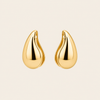 Gold teardrop earrings on a beige background