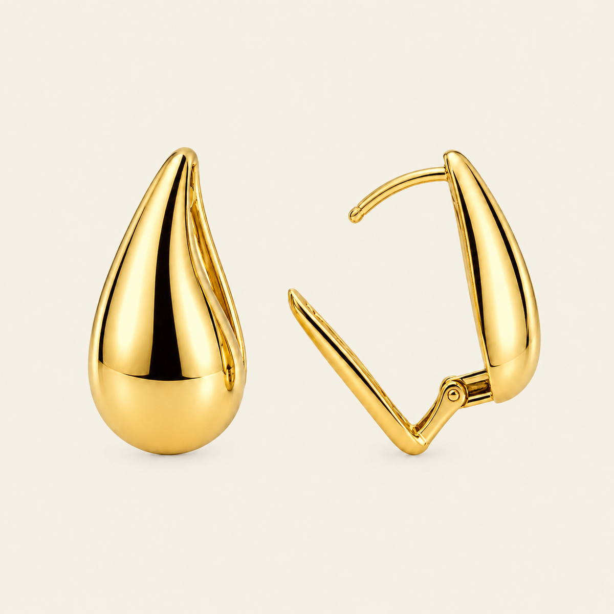 A pair of polished gold teardrop-shaped hoop earrings shown on a clean, light beige background. One earring is facing forward to show its teardrop shape, while the other is turned to the side, showing the hinged closure mechanism.