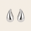 Pair of silver teardrop earrings on a beige background