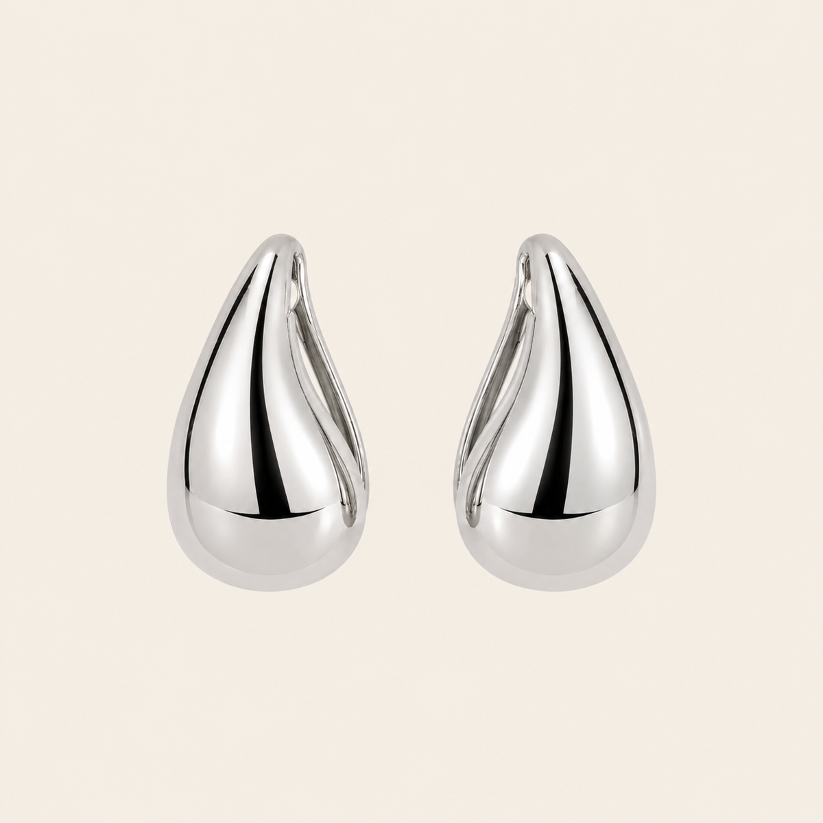 Pair of silver teardrop earrings on a beige background