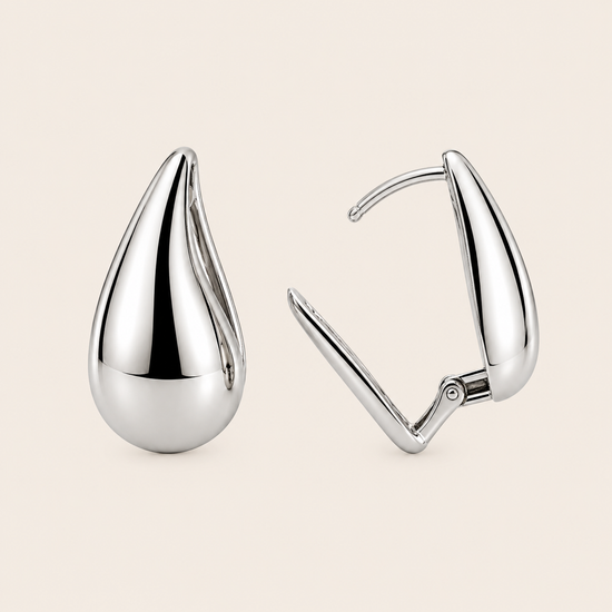 Pair of silver teardrop earrings on a beige background