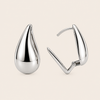 Pair of silver teardrop earrings on a beige background