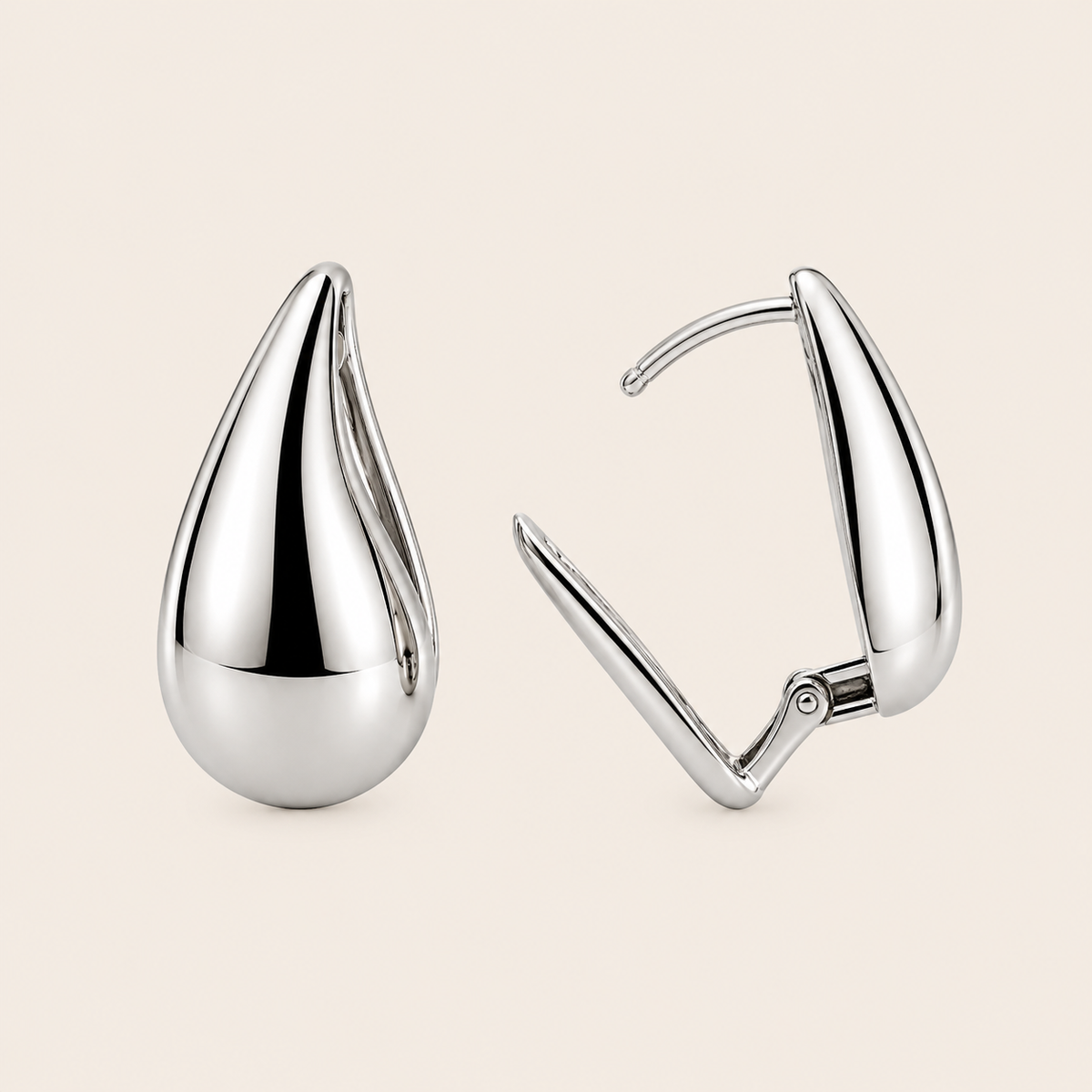 Pair of silver teardrop earrings on a beige background