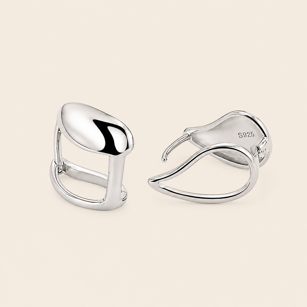 Pair of silver earrings on a beige background