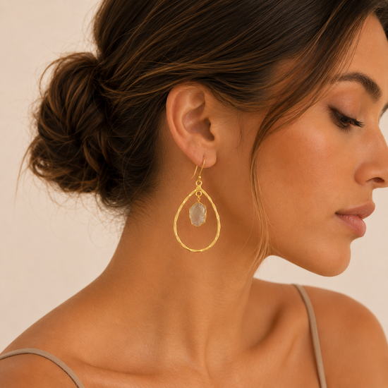 Close-up of a woman wearing gold hoop earrings with a neutral background