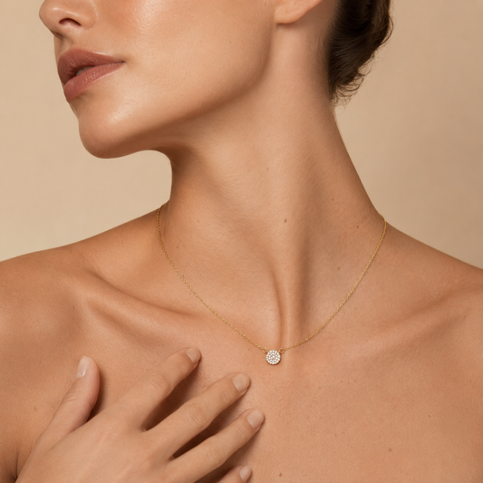Close-up of a woman wearing a gold necklace with a diamond pendant on a beige background