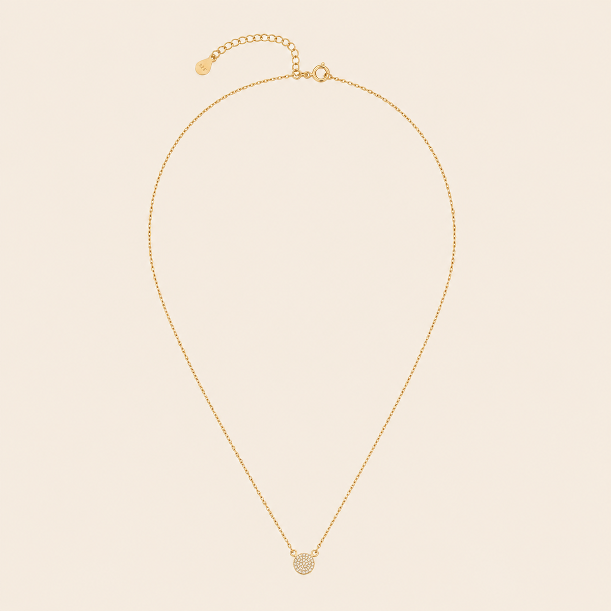 Gold necklace with a pendant on a beige background