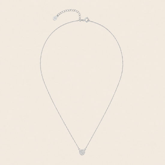 Silver necklace with a small round pendant on a beige background