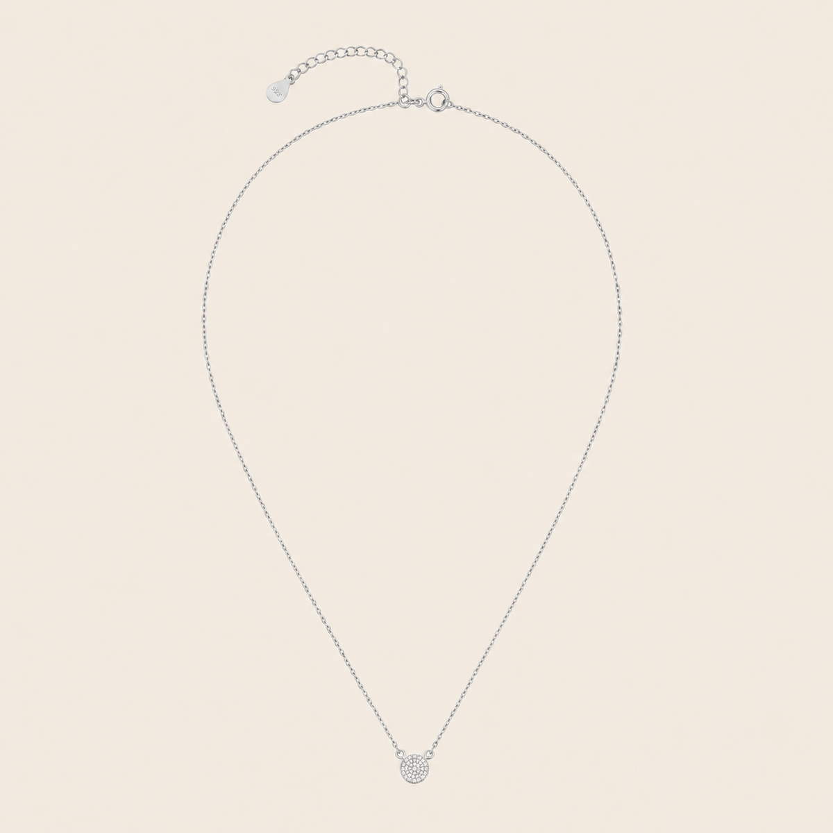 Silver necklace with a small round pendant on a beige background