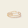 Gold open bracelet with star-shaped stones on a light beige background