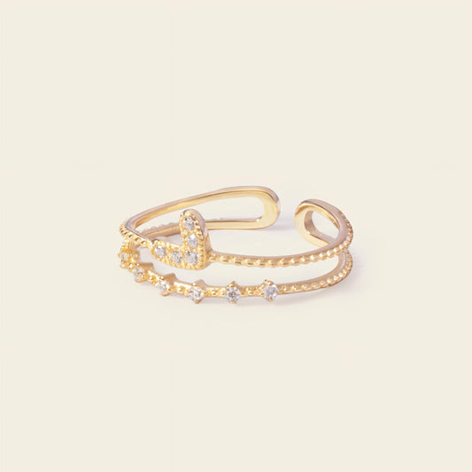 Gold open bracelet with star-shaped stones on a light beige background