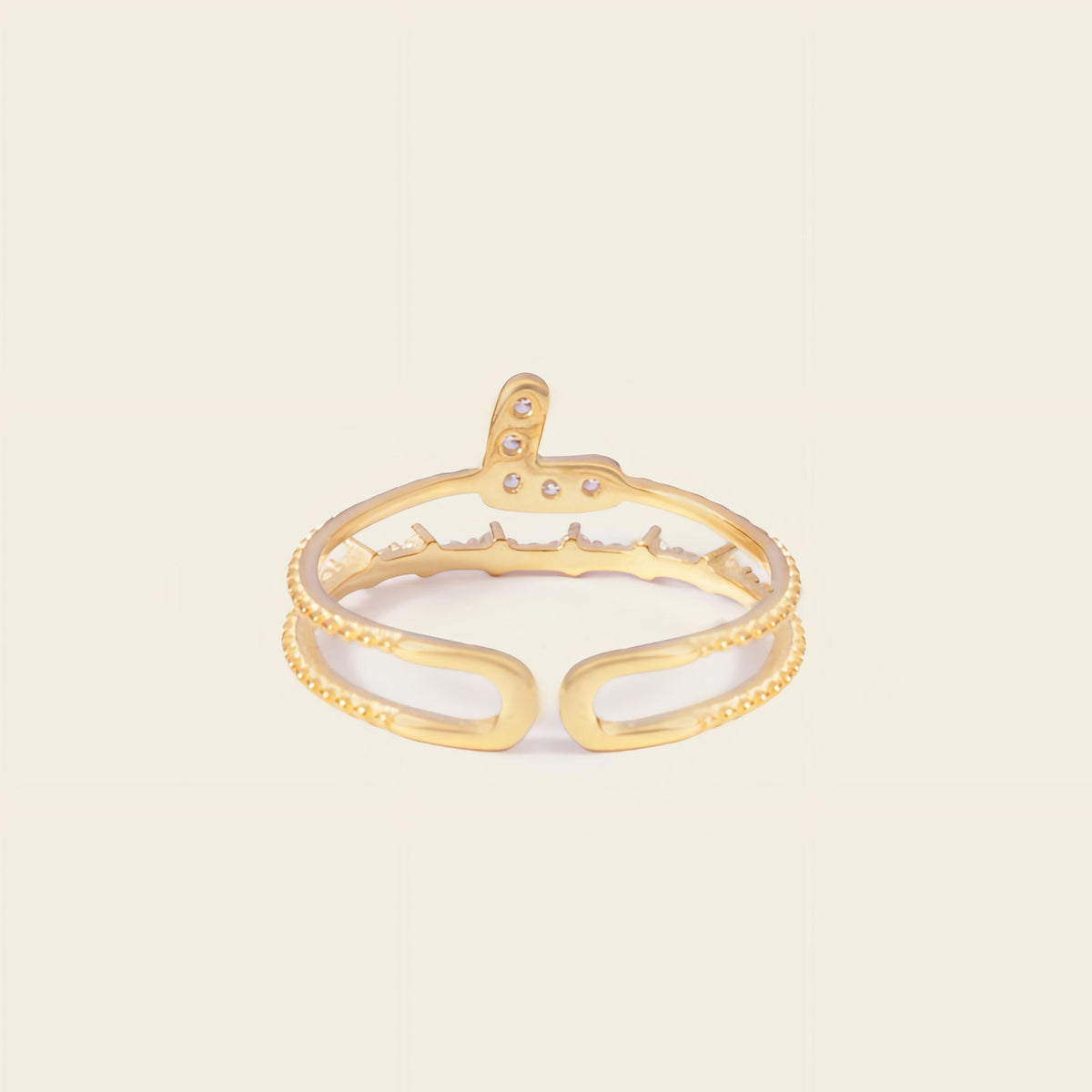 Gold open ring with small stones on a beige background