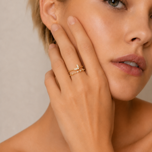Woman wearing a gold ring with a diamond on a neutral background