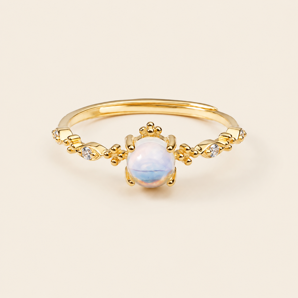 Gold ring with a central white gemstone on a beige background