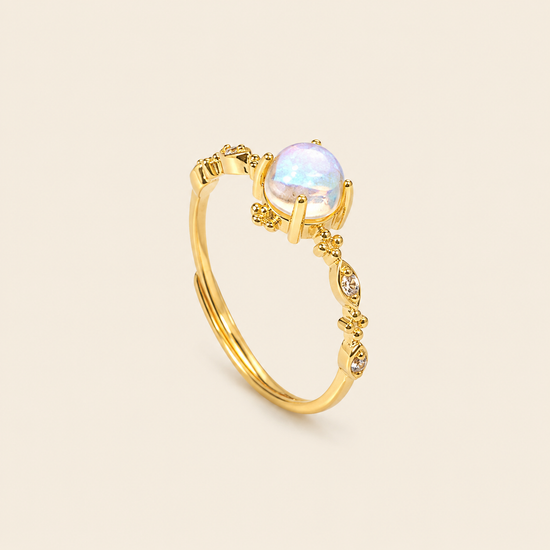 Gold ring with a white gemstone on a beige background
