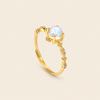 Gold ring with a white gemstone on a beige background