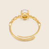 Gold ring with a central gemstone on a beige background