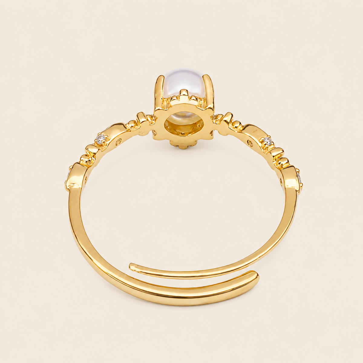 Gold ring with a central gemstone on a beige background