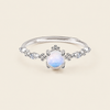 Silver ring with a white gemstone on a beige background