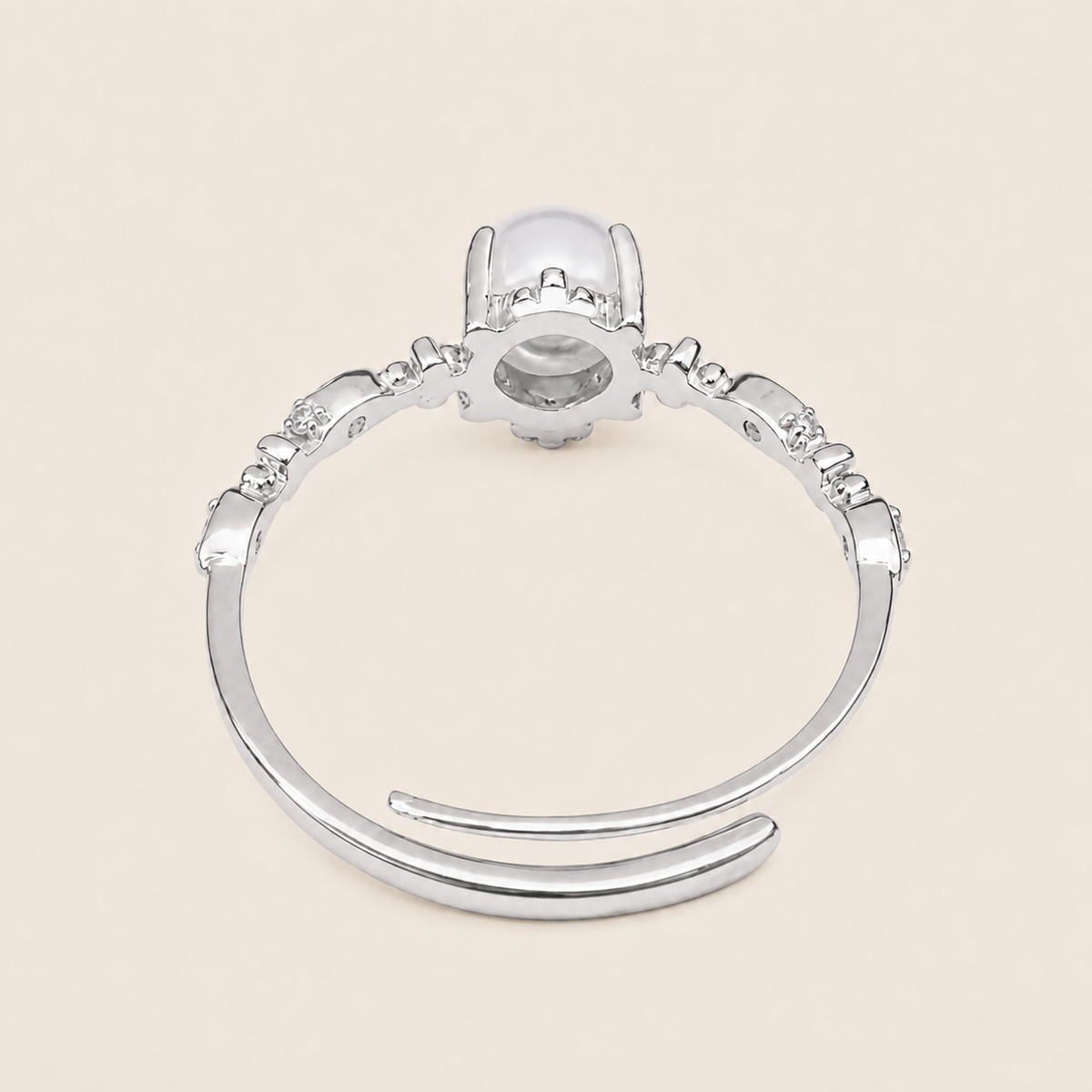 Silver ring with a central gemstone on a beige background