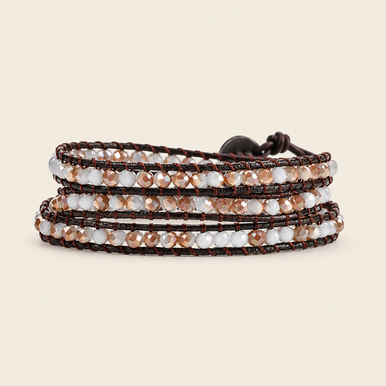 A multi-strand wrap bracelet featuring dark brown cord, clear faceted beads, and metallic rose gold beads, shown on a solid light beige background.