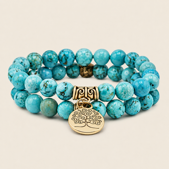 Turquoise beaded bracelet with gold tree of life charm on a beige background