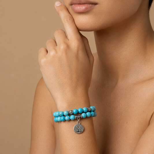 Turquoise beaded bracelet with a silver charm on a person's wrist against a beige background