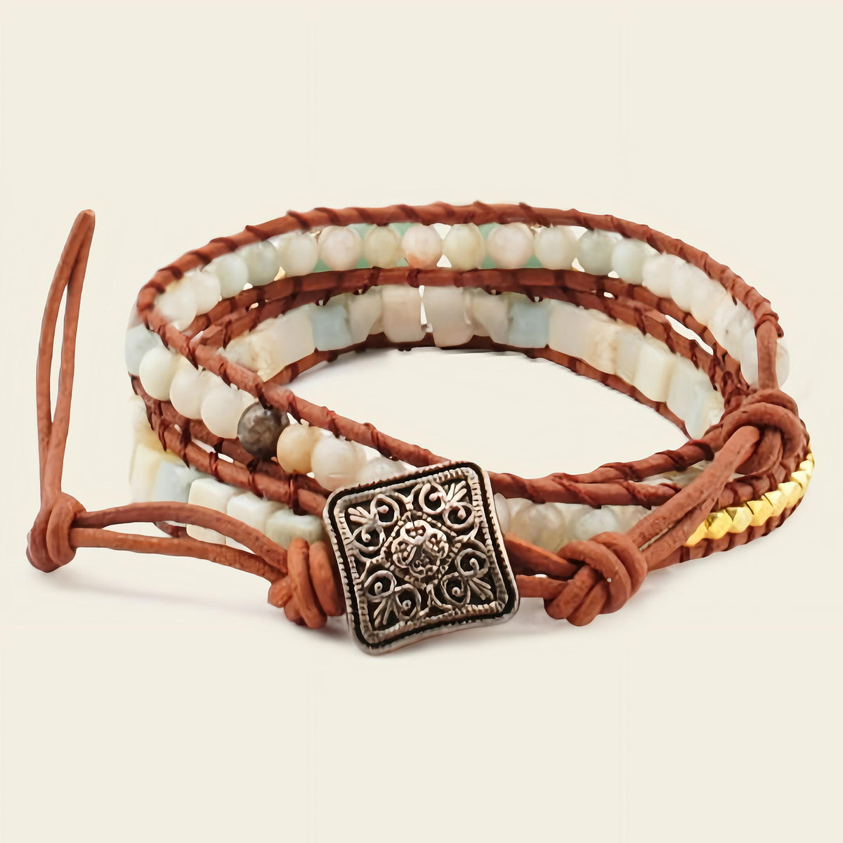 Multistrand bracelet with beads and leather strap on a beige background
