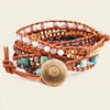 Stack of beaded bracelets with a gold coin charm on a beige background