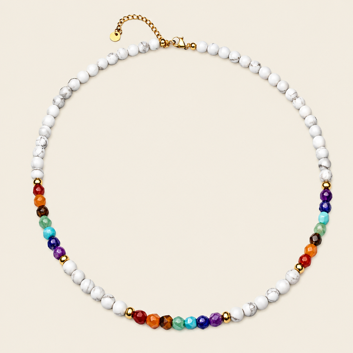 A beaded necklace featuring white marbled beads with small rainbow-colored gemstone beads at the front, accented by gold spacer beads and a gold clasp, displayed on a light beige background.