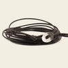 Black cord bracelet with a silver disc charm on a beige background