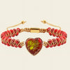 Bracelet with red beads and a heart-shaped green and red stone on a beige background