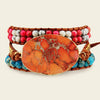 Multistrand bracelet with an orange stone centerpiece on a light background