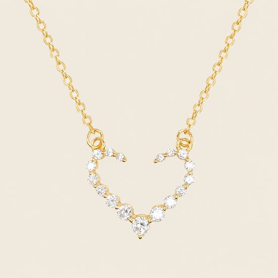 Gold necklace with a heart-shaped pendant on a beige background