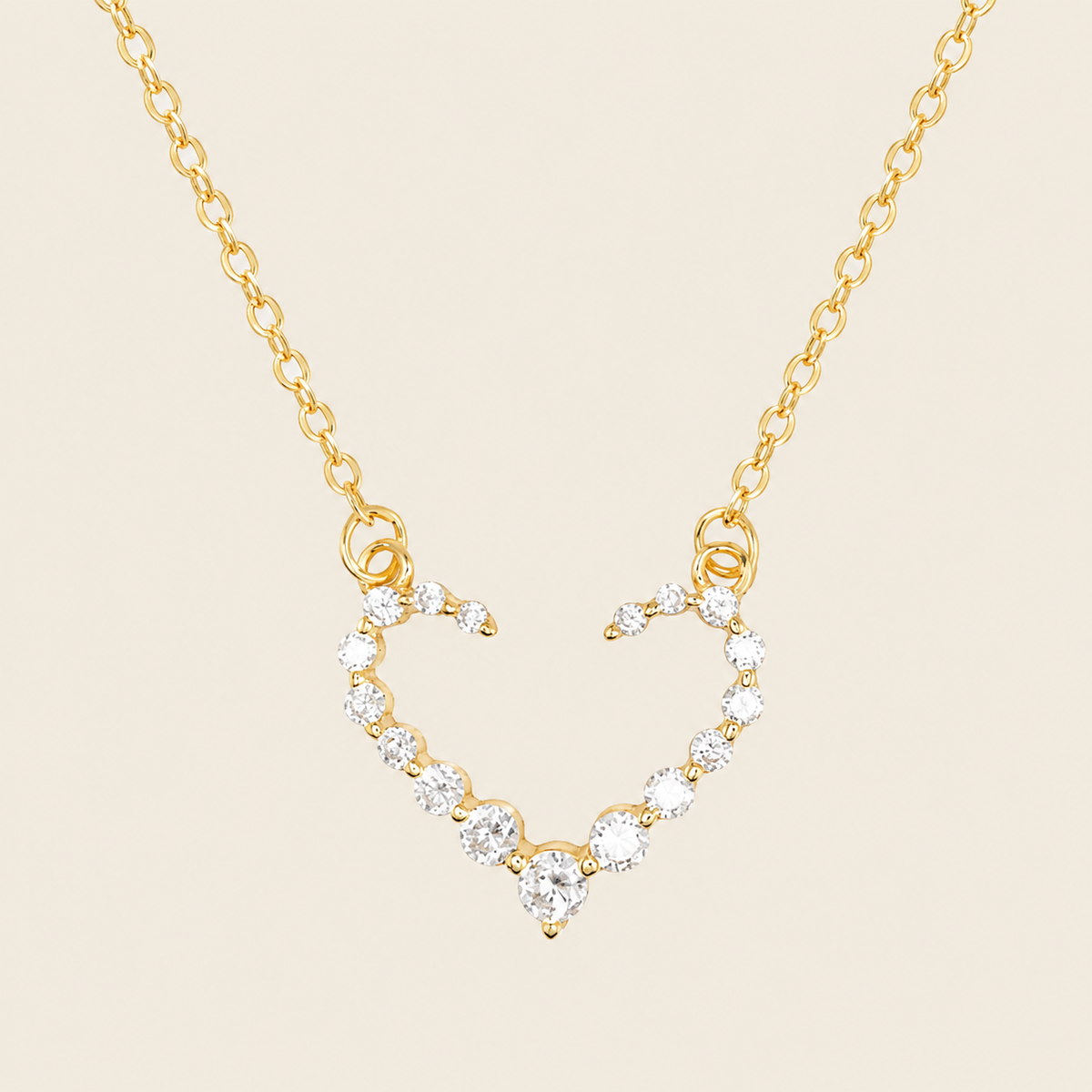 Gold necklace with a heart-shaped pendant on a beige background