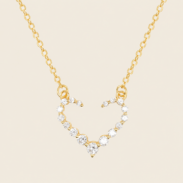 Gold necklace with a heart-shaped pendant on a beige background