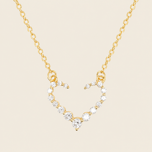 Gold necklace with a heart-shaped pendant on a beige background