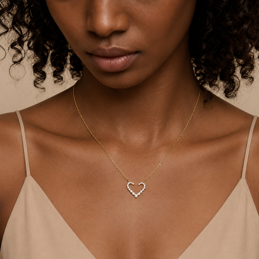 Woman wearing a gold necklace with a heart-shaped pendant on a beige background