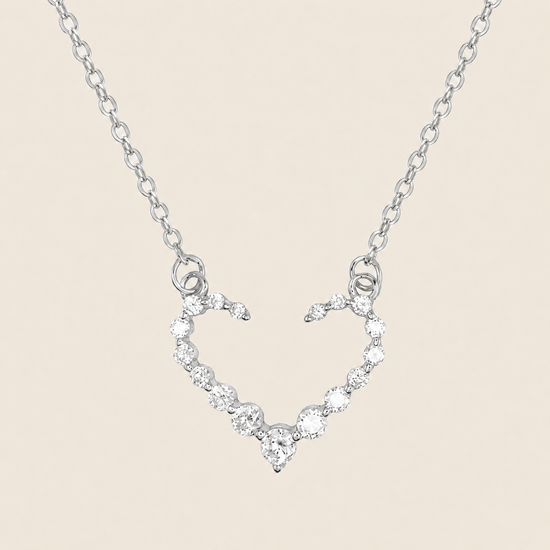 Silver necklace with a heart-shaped pendant on a beige background