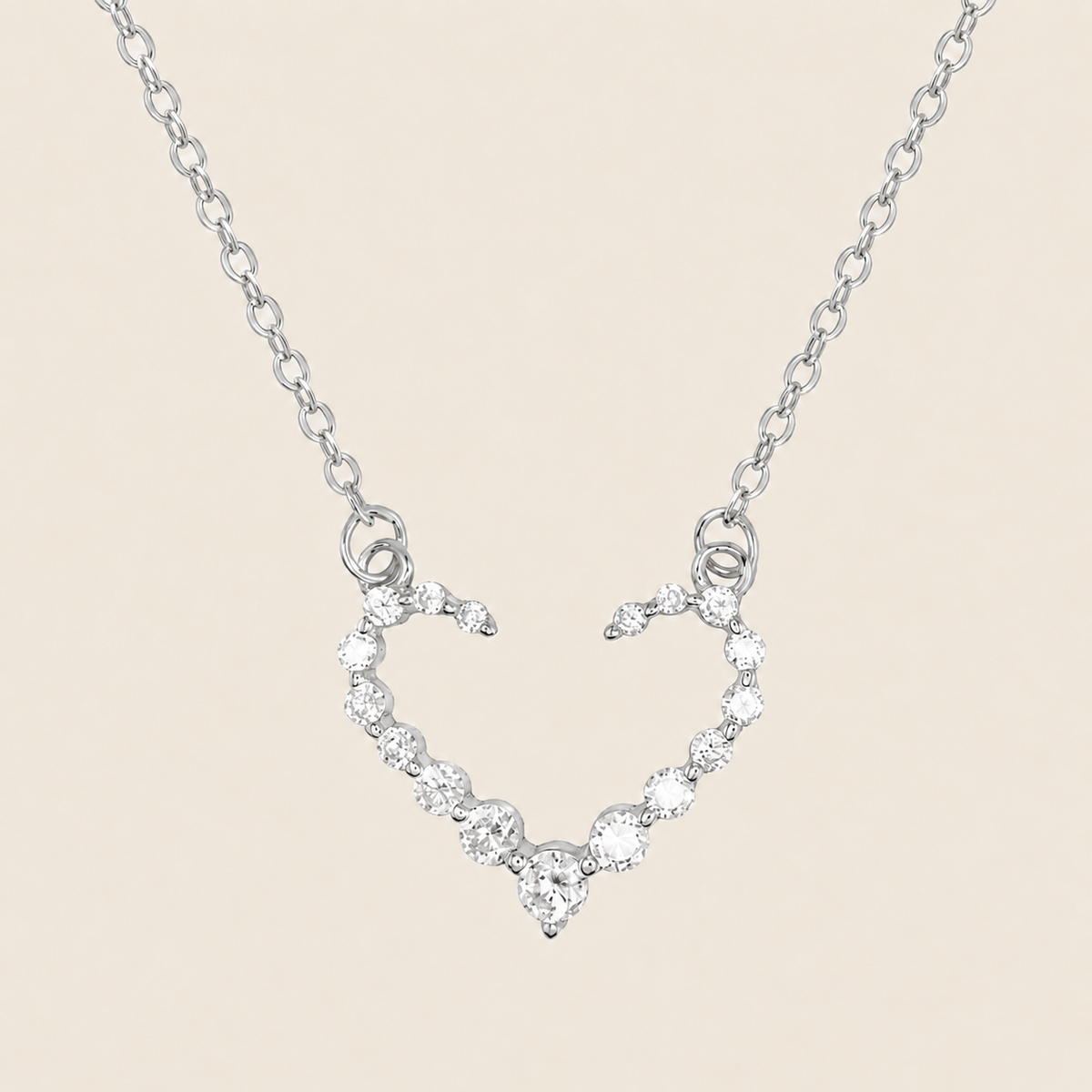 Silver necklace with a heart-shaped pendant on a beige background