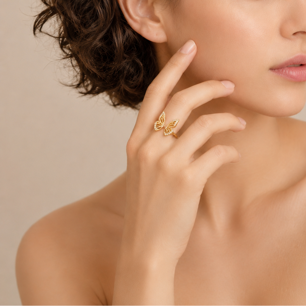 Woman wearing a gold ring with a butterfly design on a beige background