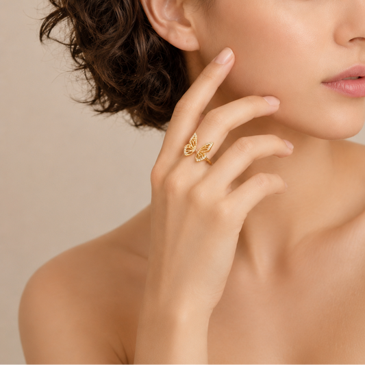 Woman wearing a gold ring with a butterfly design on a beige background