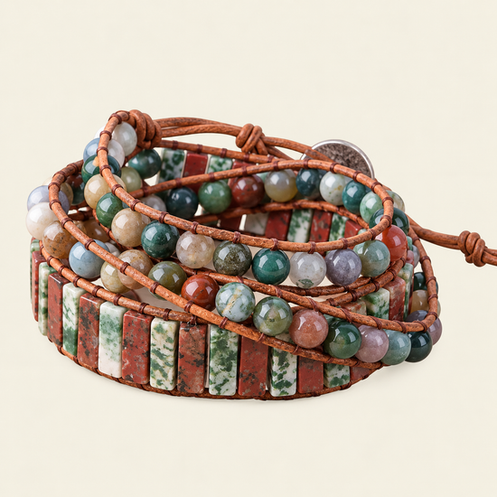 A multi-strand wrap bracelet made of brown cord and polished stone beads and rectangular stone tiles in earthy red, green, white, and gray tones, photographed on a plain light beige background.
