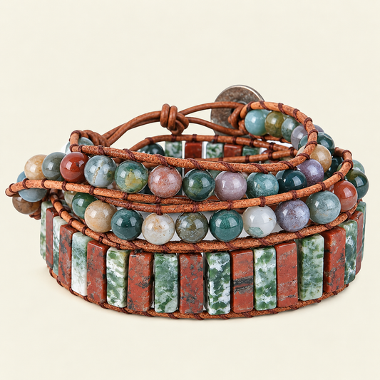 A multi-strand wrap bracelet featuring brown leather cords, round polished gemstone beads in assorted earthy colors, and rectangular red and green stone inlays, photographed on a light cream background.