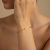Gold chain bracelet on a wrist with a neutral background