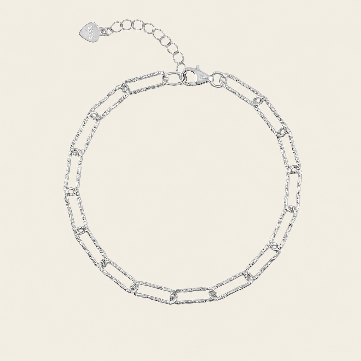 A silver chain link bracelet with elongated oval links and a lobster clasp, shown on a light beige background.