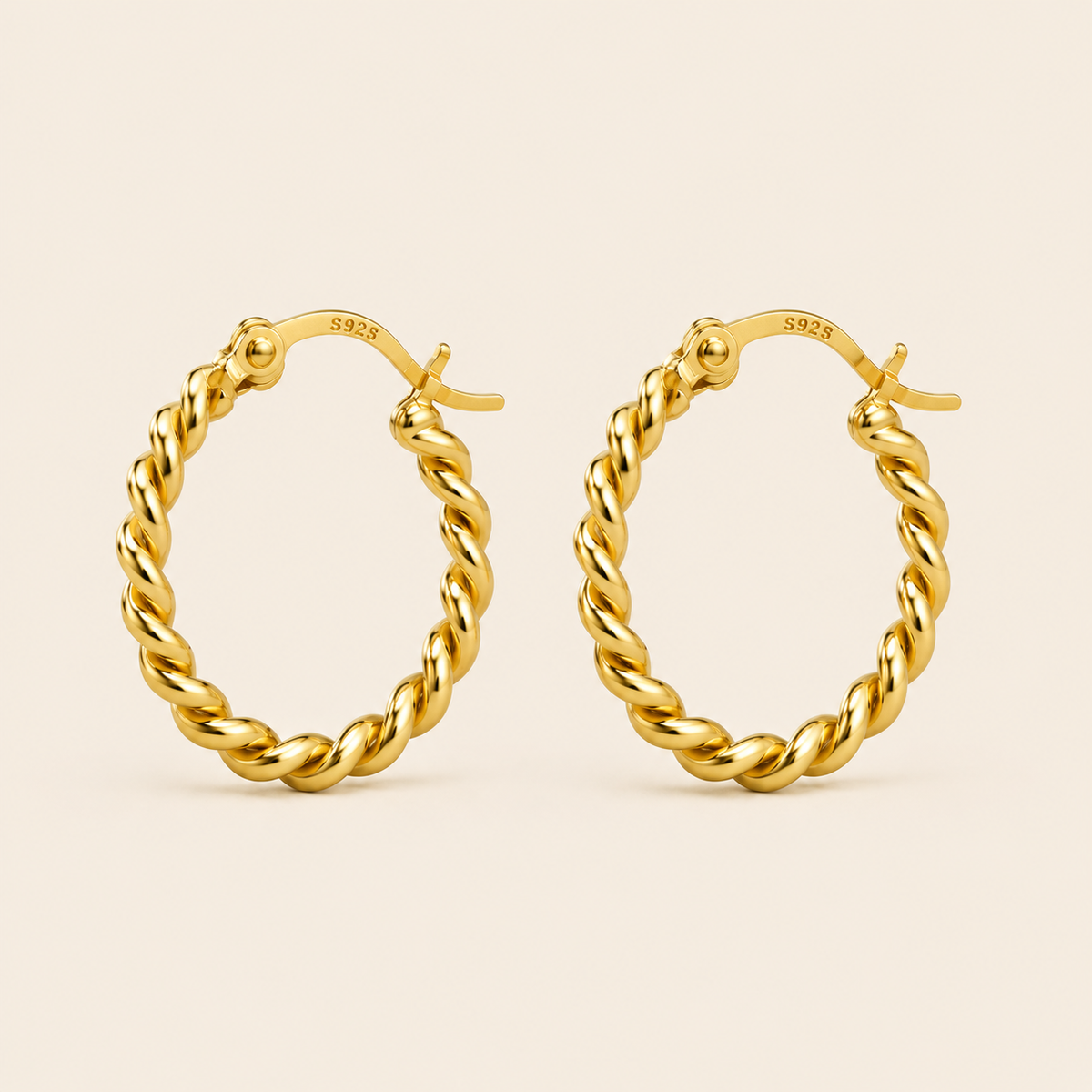 A pair of gold hoop earrings with a twisted rope design, shown on a light beige background. The inside of the hoops shows a '925' sterling silver hallmark.