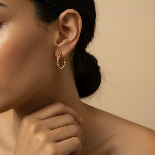 Close-up of a person wearing a gold hoop earring against a beige background