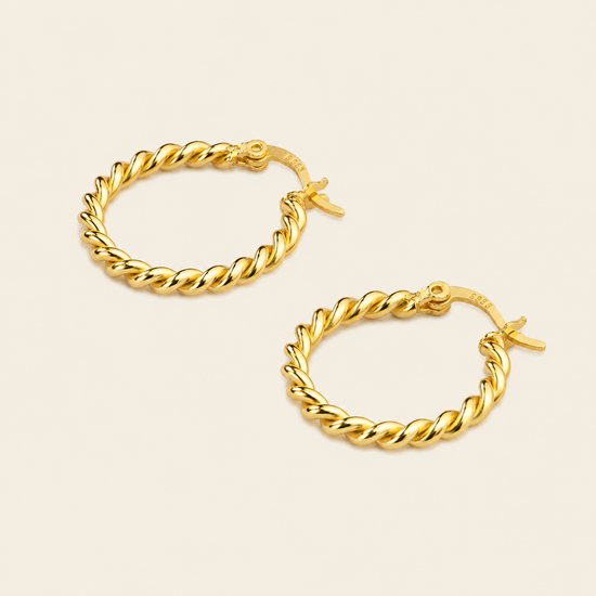 A pair of gold hoop earrings with a twisted rope design, displayed on a light beige background.