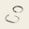 Two silver hoop earrings on a light beige background